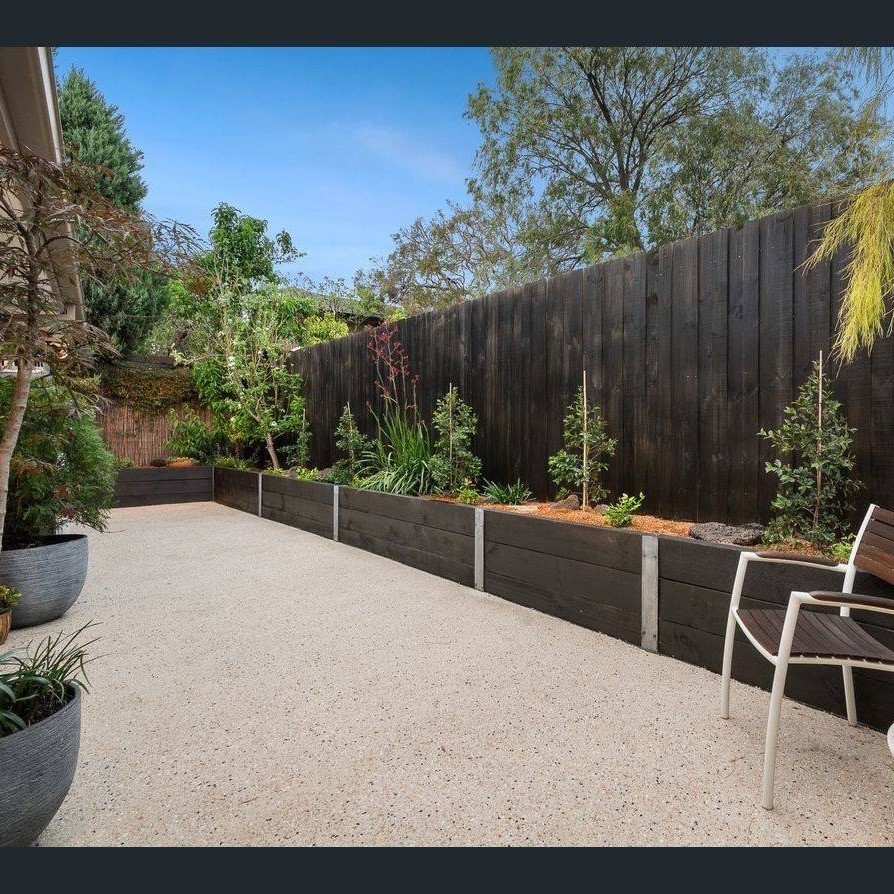 bright exposed aggregate concrete courtyard complimented with Saturn stained wood grain sleeper walls with Australian natives plantings (2)